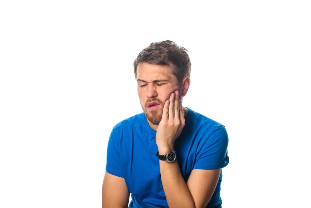 Man in need of an emergency dentist holding his Jaw
